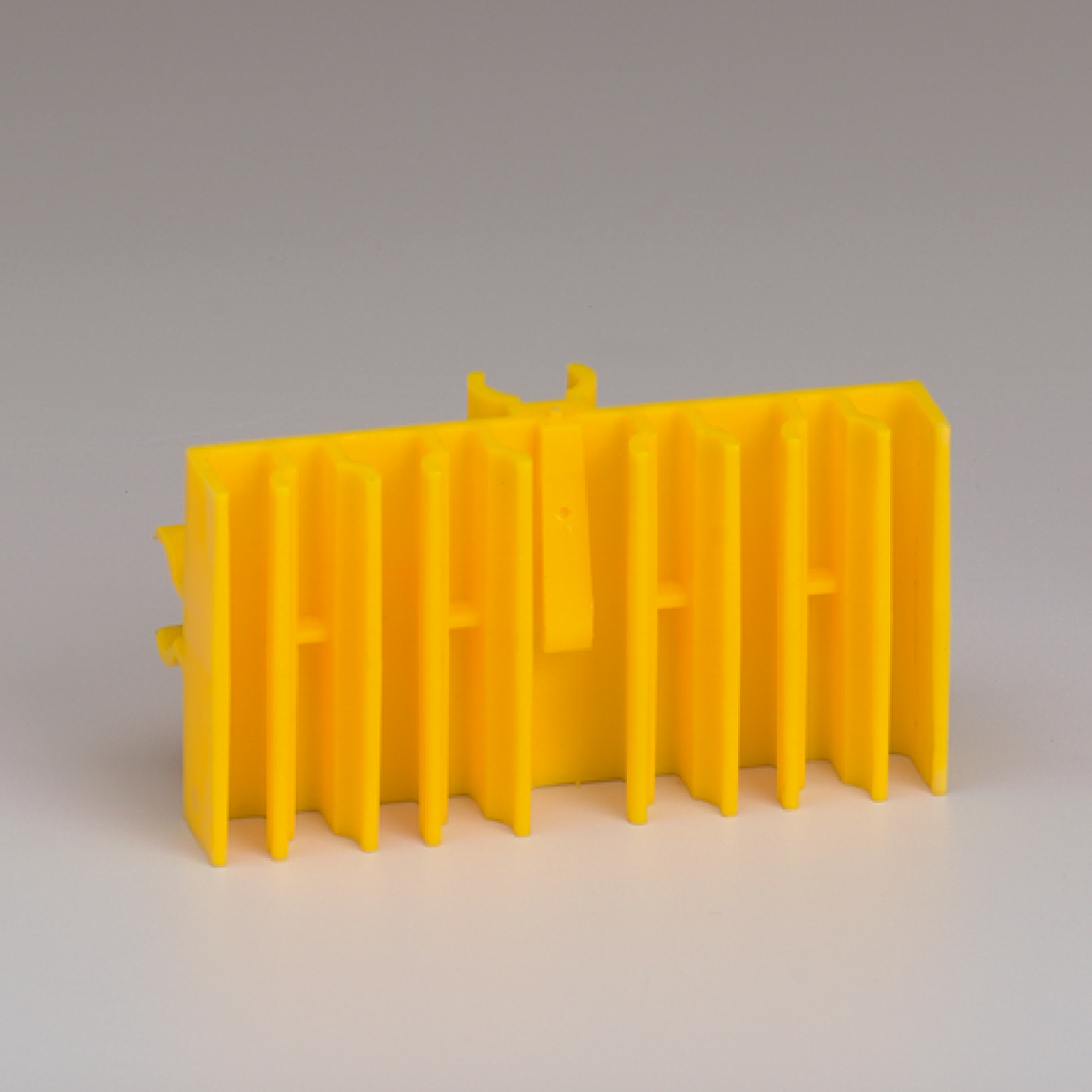 Das Bild zeigt ein leuchtend gelbes Experimentiergerät, das mehrere vertikale Rillen aufweist. Es scheint für Bildungszwecke im naturwissenschaftlichen Unterricht konzipiert zu sein.