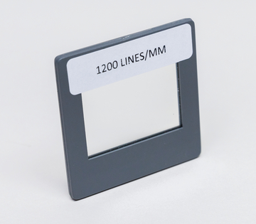 Das Bild zeigt einen optischen Filter mit der Beschriftung "1200 LINES/MM". Dieser Filter wird häufig im Experimentierbedarf für das Bildungswesen eingesetzt, um Lichtstrahlen zu analysieren oder zu überprüfen.