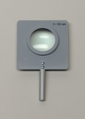 Das Bild zeigt eine graue Lupe mit einem Durchmesser von etwa 50 mm, die auf einem neutralen Hintergrund platziert ist. Die Lupe hat einen stabilen Griff und einen klaren, großen Linseneinsatz für genaues Betrachten von Objekten.