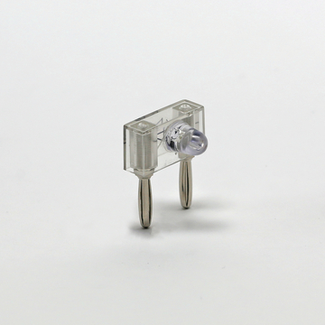 Das Bild zeigt ein transparentes elektronisches Bauteil mit einer LED und zwei Metallanschlüssen. Es wird vermutlich für experimentelle Zwecke im Bildungsbereich verwendet, um elektrische Schaltungen zu demonstrieren.