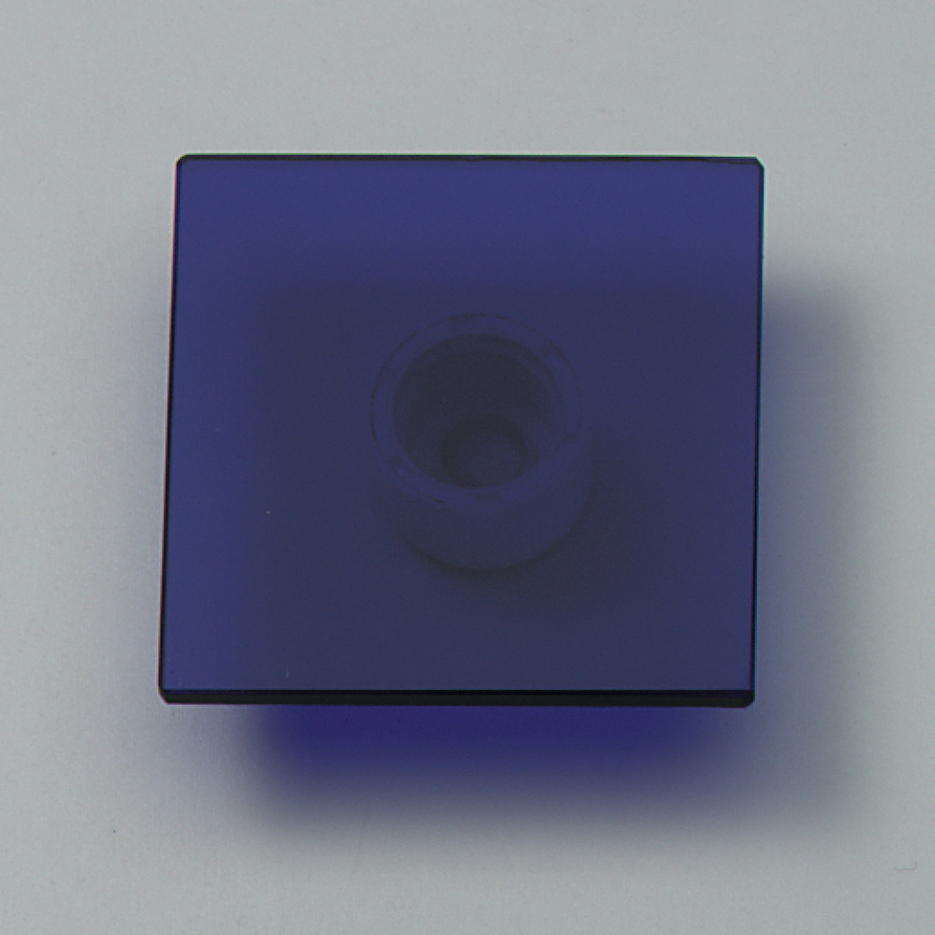 Das Bild zeigt eine quadratische, blauen Glasplatte mit einer Vertiefung in der Mitte. Diese könnte für Experimente im Bereich Optik oder Lichtbrechung verwendet werden.