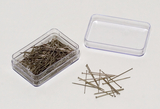 Das Bild zeigt eine transparente Box mit einer Vielzahl von metallischen Stecknadeln, die teilweise noch darin liegen und teilweise daneben angeordnet sind. Die Pins scheinen für experimentelle oder schulische Zwecke gedacht zu sein.