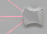 Das Bild zeigt eine durchsichtige, gewölbte Linse, durch die mehrere rote Laserstrahlen scheinen. Die Strahlen brechen sich und zeigen, wie Licht durch die Linse gelenkt wird, was eine praktische Demonstration von optischen Prinzipien darstellt.