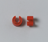 Das Bild zeigt zwei rote Kunststoffteile, die möglicherweise für experimentelle oder technische Anwendungen gedacht sind. Das linke Teil hat eine offene, gebogene Form, während das rechte Teil eine gerade, kompakte Form aufweist.