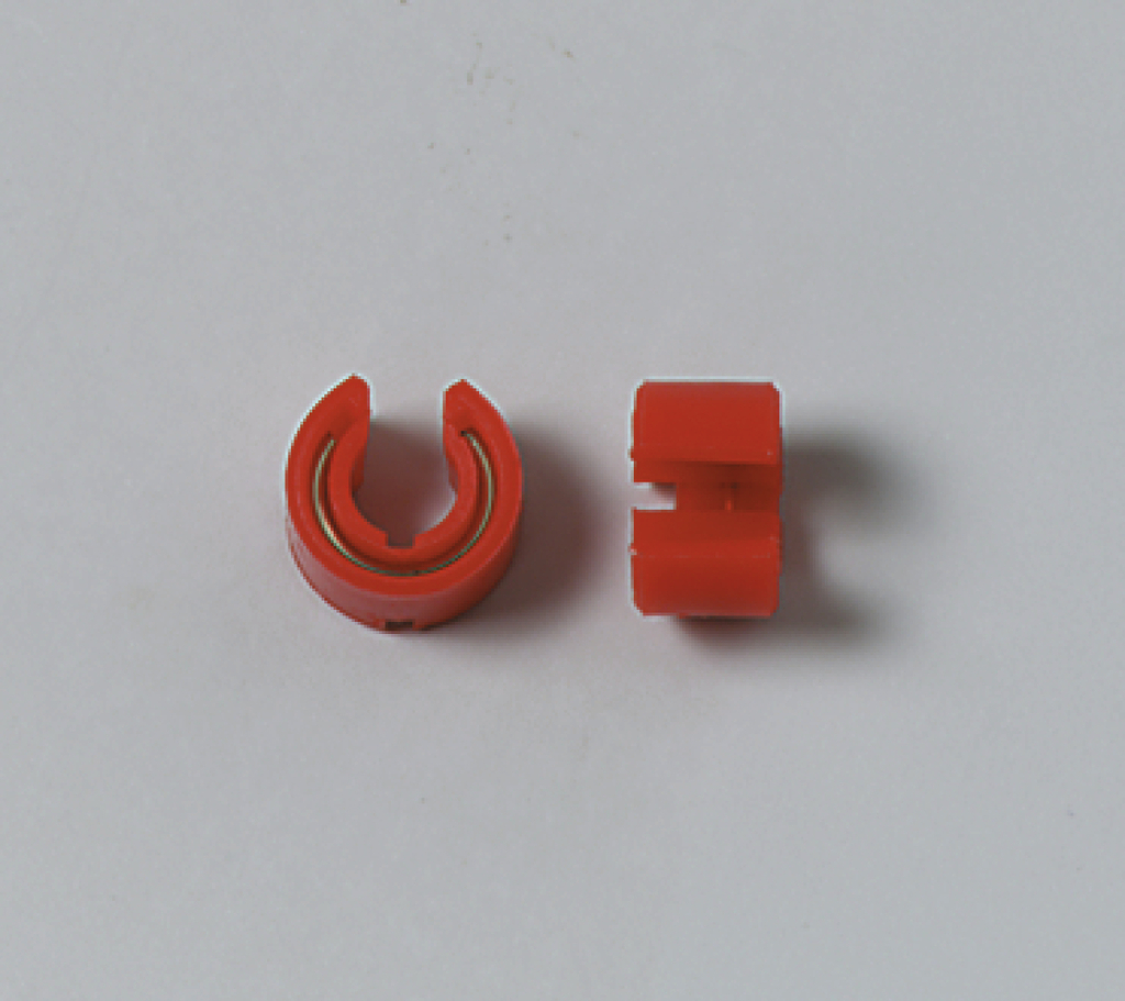 Das Bild zeigt zwei rote Kunststoffteile, die möglicherweise für experimentelle oder technische Anwendungen gedacht sind. Das linke Teil hat eine offene, gebogene Form, während das rechte Teil eine gerade, kompakte Form aufweist.