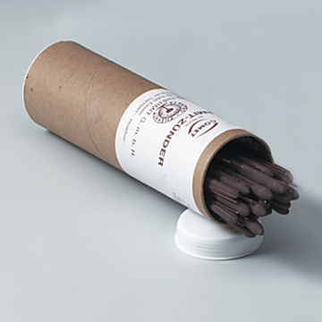 Das Bild zeigt eine runde Pappverpackung, die mehrere dunkle, stiftähnliche Gegenstände enthält. Die Verpackung hat ein Etikett mit Informationen zum Inhalt und einer weißen Drehkappe.