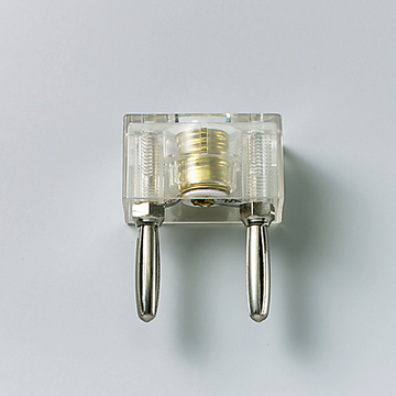 Das Bild zeigt ein transparentes Experimentiergerät mit zwei metallischen Kontakten und einer zentralen goldenen Komponente. Es dient vermutlich zur Durchführung von physikalischen Experimenten im Bildungswesen.