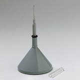 Das Bild zeigt einen grauen Trichter mit einer langen Spitze, der für wissenschaftliche Experimente verwendet wird. Neben dem Trichter liegt ein kleines, transparentes Röhrchen.