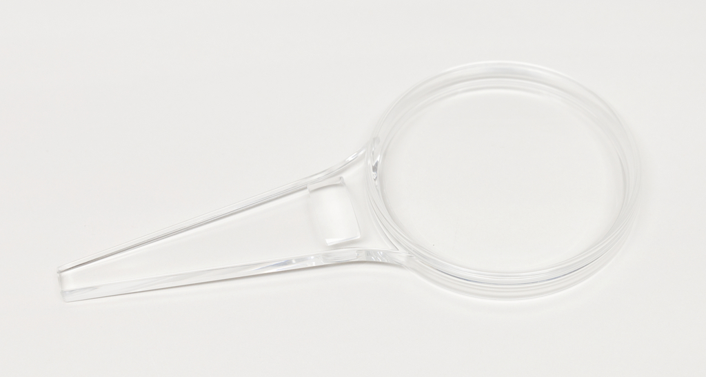 Das Bild zeigt eine transparente Kunststofflupe mit einem ergonomischen Griff. Sie ist für educational Zwecke im Experimentierbedarf konzipiert und ermöglicht das Vergrößern von Objekten zur besseren Beobachtung.