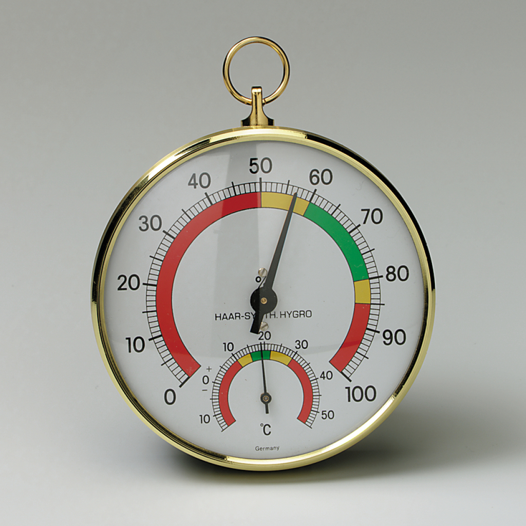 Das Bild zeigt ein analoges Thermo-Hygrometer mit einer goldenen Rahmenkonstruktion. Es misst die Temperatur in Grad Celsius und die Luftfeuchtigkeit, dargestellt durch eine farbige Skala in Grün, Gelb und Rot.