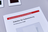 Das Bild zeigt eine Anleitung für Zubehör zur Farbmischnung, die Teil eines Experimentierpakets ist. Neben der Anleitung befinden sich verschiedene Farbproben auf einem neutralen Hintergrund.
