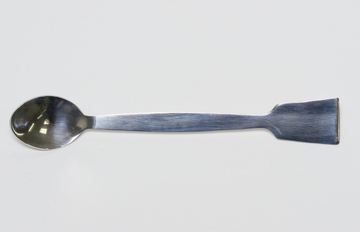 Das Bild zeigt einen Edelstahl-Löffel mit einer flachen, breiten Seite und einer ovalen Löffelform. Dieser Löffel könnte für Experimente in der Schule oder im Labor eingesetzt werden, um verschiedene Substanzen zu mischen oder zu bewegen.