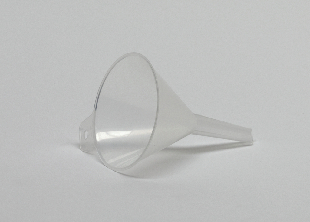 Das Bild zeigt einen transparenten Kunststofftrichter, der auf einer weißen Unterlage liegt. Er ist kegelförmig mit einem langen Auslauf und einer seitlichen Aussparung für die Handhabung und wird häufig in Experimenten verwendet.