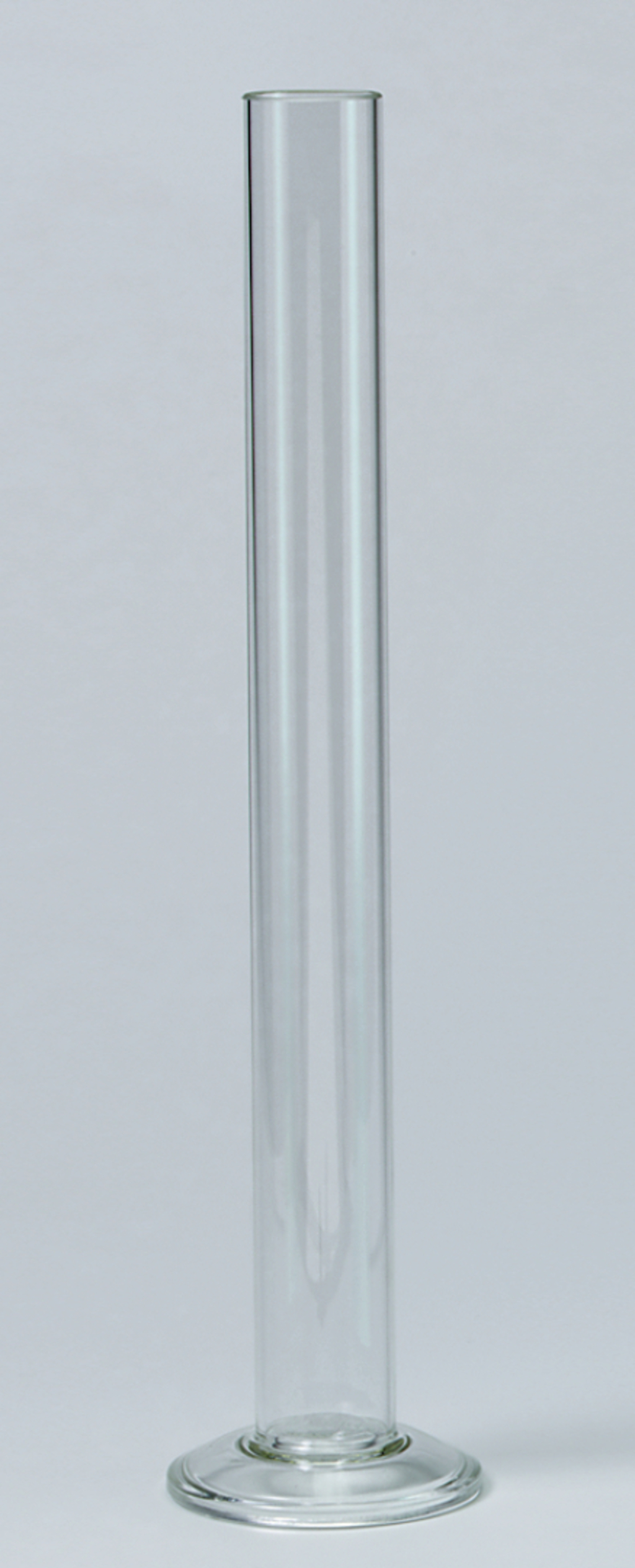 Das Bild zeigt ein hohes, klares Reagenzglas mit einem stabilen, runden Fuß. Es wird häufig im Bildungsbereich für chemische Experimente und Darstellungen von Lösungen verwendet.