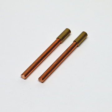 Das Bild zeigt zwei Stäbe aus Kupfer mit einer Messinghülse am oberen Ende. Diese Komponenten sind typischerweise in Experimenten für das deutsche Bildungswesen verwendet, um verschiedene physikalische oder chemische Phänomene zu demonstrieren.