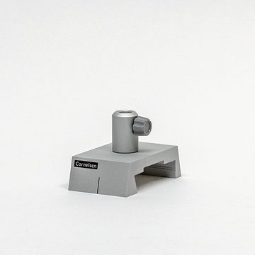 Das Bild zeigt einen grauen Experimentieraufbau aus einem Online-Shop für Bildungseinrichtungen. Er besteht aus einer stabilen Basis mit einem vertikalen Röhrchen und Drehknopf, vermutlich zur Durchführung chemischer Experimente.