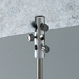 Das Bild zeigt ein metallisches Halterungselement mit mehreren Einstellschrauben, das an einer Arbeitsfläche fixiert ist. Es dient zur Befestigung von Experimentiergeräten und ist Teil des Zubehörs für schulische Experimente im naturwissenschaftlichen Bereich.