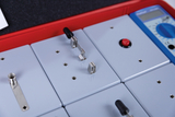 Das Bild zeigt eine Experimentierstation mit mehreren grauen Modulen, die mit verschiedenen elektrischen Bauteilen ausgestattet sind. Ein digitales Multimeter ist ebenfalls enthalten, um Messungen durchzuführen und die Versuchsreihen zu unterstützen.