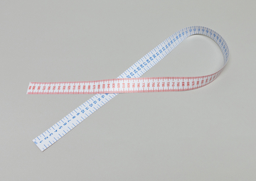 Das Bild zeigt ein flexibles Maßband, das auf einer neutralen Oberfläche liegt. Es ist auf der einen Seite blau und auf der anderen Seite rot, mit klaren numerischen Markierungen für präzise Messungen.