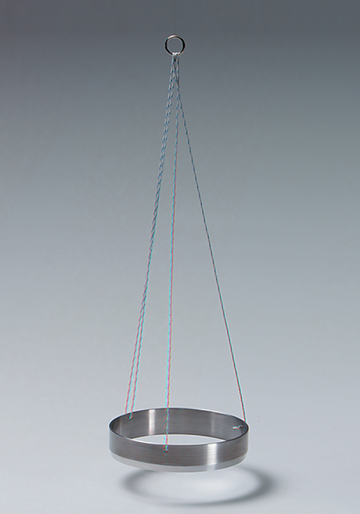 Das Bild zeigt einen schlichten, metallenen Ring, der an zwei Schnüren aufgehängt ist. Er dient vermutlich als Experimentiermaterial zur Untersuchung physikalischer Eigenschaften wie Schwingungen oder Gleichgewicht.