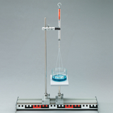 Das Bild zeigt ein physikalisches Experimentier-Setup mit einem hängenden Messgerät und einem transparenten Behälter, der mit blauer Flüssigkeit gefüllt ist. Es ist auf einer stabilen Basis montiert, die präzise Messungen ermöglicht.