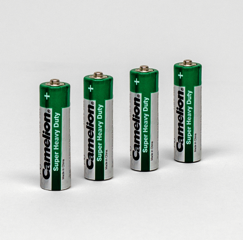 Das Bild zeigt vier grüne Batterien der Marke Camelion mit der Aufschrift "Super Heavy Duty". Sie sind nebeneinander auf einem weißen Hintergrund angeordnet.