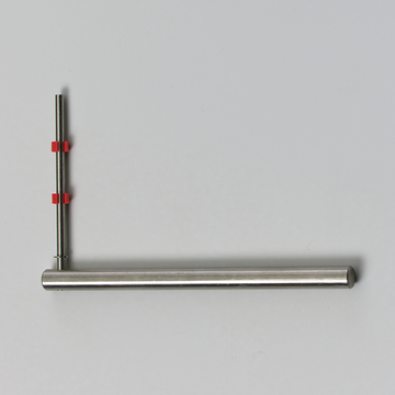 Das Bild zeigt ein experimentelles Gerät, das aus einem langen, geraden Metallrohr und einem vertikalen Stab besteht. Beide Teile sind mit roten Halterungen verbunden, die eine flexible Positionierung ermöglichen.