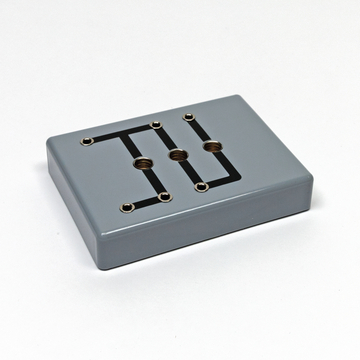 Das Bild zeigt ein graues Experimentiergerät mit mehreren Anschlüssen und einer schwarzen Leitungsführung auf der Oberfläche. Es ist wahrscheinlich für Bildungszwecke im naturwissenschaftlichen Bereich konzipiert.