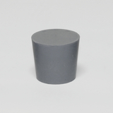 Das Bild zeigt einen grauen, zylindrischen Block aus Kunststoff mit einer flachen Oberseite. Dieses Experimentiermaterial könnte in verschiedenen wissenschaftlichen Anwendungen im Bildungsbereich verwendet werden.