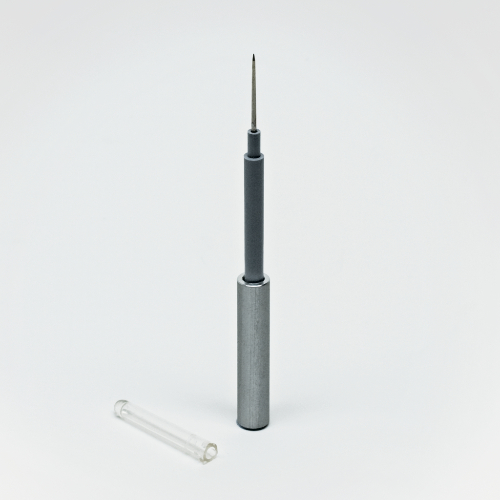 Das Bild zeigt eine Metallspitze, die im Kontext von Experimentierbedarf verwendet wird, zusammen mit einem transparenten Röhrchen daneben. Diese Komponenten könnten Teil eines Geräts zum Messen oder Testen in Bildungsumgebungen sein.