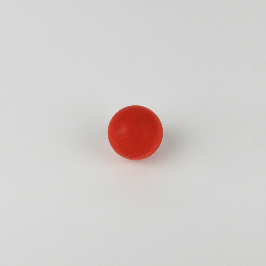 Das Bild zeigt eine rote Kugel auf einem weißen Hintergrund. Die Kugel scheint aus einem glatten Material gefertigt und wird möglicherweise für experimentelle Zwecke im Bildungsbereich verwendet.