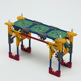 Das Bild zeigt eine Konstruktion aus bunten Bauelementen, die einen stabilen Tisch oder eine Plattform darstellt. Die Bauteile sind in verschiedenen Farben angeordnet und bieten eine Vielzahl von Verbindungsmöglichkeiten für Experimente im Bildungsbereich.