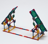 Das Bild zeigt eine Konstruktion aus bunten Bauelementen, die vermutlich als Experimentiermaterial im Bildungsbereich dient. Die Struktur hat schräg angeordnete Platten, die auf einer stabilen Basis montiert sind und möglicherweise für physikalische Experimente genutzt werden können.