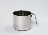 Das Bild zeigt einen silbernen Messbecher aus Edelstahl mit einem Griff. Der Becher hat eine glatte Oberfläche und ist am unteren Rand mit mehreren horizontalen Linien verziert.