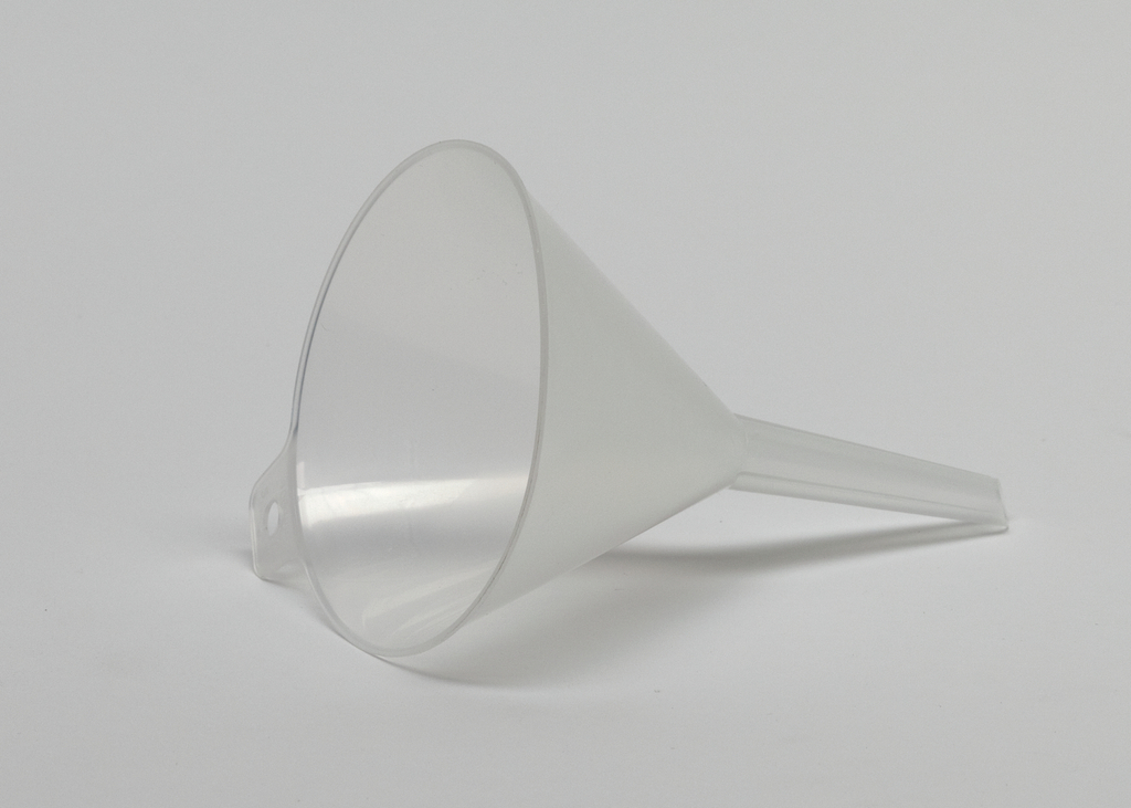 Das Bild zeigt einen transparenten Kunststofftrichter, der schräg auf einer weißen Oberfläche liegt. Er wird häufig in Experimenten verwendet, um Flüssigkeiten sicher in Behälter zu gießen.