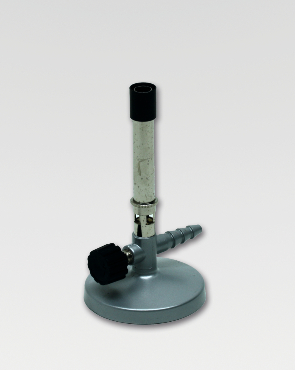 Das Bild zeigt einen Bunsenbrenner, der aus einem Metallfuß, einem verstellbaren Regler und einem langen Rohr besteht. Dieses Gerät wird häufig in Experimenten zur Erwärmung von Substanzen in Schulen verwendet.