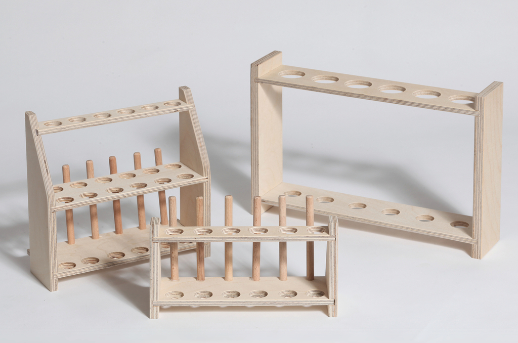 Das Bild zeigt drei verschiedene Ständer aus Holz, die für das Halten von Experimentiergefäßen konzipiert sind. Sie bestehen aus mehreren Löchern und Holzstäben, die eine stabile Ablage bieten und sind ideal für den Einsatz im Bildungsbereich.