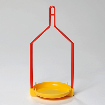 Das Bild zeigt einen Experimentierständer mit einem roten Metallrahmen und einer gelben Kunststoffschale. Dieses Gerät wird häufig in Schulversuchen verwendet, um verschiedene Materialien aufzunehmen oder zu präsentieren.