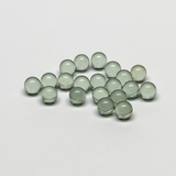 Das Bild zeigt eine Ansammlung von kleinen, transparenten Glaskugeln in verschiedenen Grüntönen. Sie sind gleichmäßig geformt und auf einer hellen Oberfläche angeordnet, was darauf hinweist, dass sie als Experimentiermaterial verwendet werden könnten.