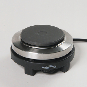 Das Bild zeigt eine elektrische Heizplatte mit einem schwarzen, rutschfesten Auflagenbereich und einem Edelstahlring. Sie ist für den Einsatz im Bildungswesen konzipiert, um Experimente und chemische Reaktionen zu unterstützen.