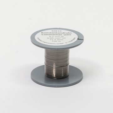 Das Bild zeigt eine Spule mit Konstantandraht, der einen Durchmesser von 0,2 mm hat und in einer Länge von 100 Metern erhältlich ist. Die Spule ist grau und weist Informationen zu den technischen Spezifikationen auf, die für Experimente im Bildungswesen genutzt werden können.