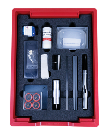 Das Bild zeigt ein Experimentierkit, das in einer roten Box angeordnet ist, mit verschiedenen Materialien wie Eisenpulver, einem Magneten und mehreren Rohren. Dieses Set ist für schulische Experimente im Bereich der Physik und Magnetismus konzipiert.