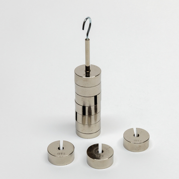 Das Bild zeigt einen Satz von Metallgewichten, die auf einem Hakenstapel angeordnet sind. Daneben befinden sich weitere runde Gewichte, die für Experimentierzwecke im Bildungsbereich verwendet werden können.