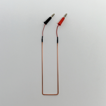 Das Bild zeigt einen elektrischen Draht mit zwei Anschlussklemmen, eine schwarz und die andere rot, die für Experimente verwendet werden können. Der Draht ist flexibel geformt und eignet sich für den Einsatz in Laboren oder Schulprojekten im Bildungsbereich.