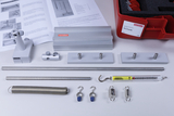 Das Bild zeigt ein Experimentierset zur Mechanik, bestehend aus verschiedenen metallischen Bauteilen wie Stangen, Feder und Haken, sowie einem Kraftmesser. Zudem sind Anleitungen und eine rote Aufbewahrungsbox zu sehen, die das Set komplett machen.