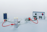 Das Bild zeigt ein Experimentier-Set zur Elektrolyse mit einem Solarmodul, zwei Messzylindern für Wasserstoff und Sauerstoff sowie einem Steuergerät zur Regulierung von Strom und Spannung. Es dient zur Demonstration der Wasserstoffproduktion durch elektrolytische Prozesse.