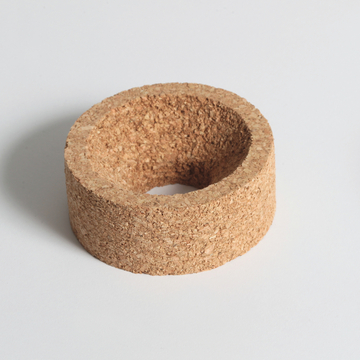 Das Bild zeigt einen zylindrischen Korkring mit einer zentralen Öffnung. Er könnte für Experimente im Bereich Physik oder Chemie verwendet werden, beispielsweise zur Stabilisierung von Behältern oder als Halterung für verschiedene Materialien.