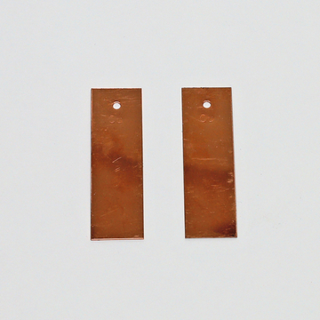 Das Bild zeigt zwei rechteckige Kupferplatten mit einem Loch an der oberen Kante. Diese Platten sind typischerweise für Experimente in der Elektrizitätslehre oder Chemie im Bildungsbereich geeignet.