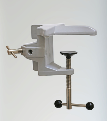 Das Bild zeigt einen grauen Versuchsschraubstock, der für Experimentierzwecke im Bildungswesen konzipiert ist. Er verfügt über eine einstellbare Schraube und eine stabile Basis, um Objekte sicher fixieren zu können.