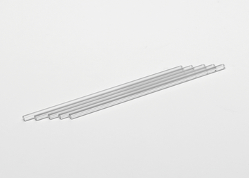 Das Bild zeigt eine Reihe transparenter Glasröhrchen, die ordentlich nebeneinander auf einer weißen Fläche liegen. Diese Röhrchen sind typischerweise für chemische Experimente oder als Laborbedarf im Bildungsbereich gedacht.
